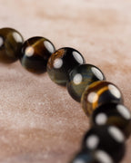 Pulsera de Ojo de Tigre Bicolor en perspectiva, cuentas redondas sobre piedra