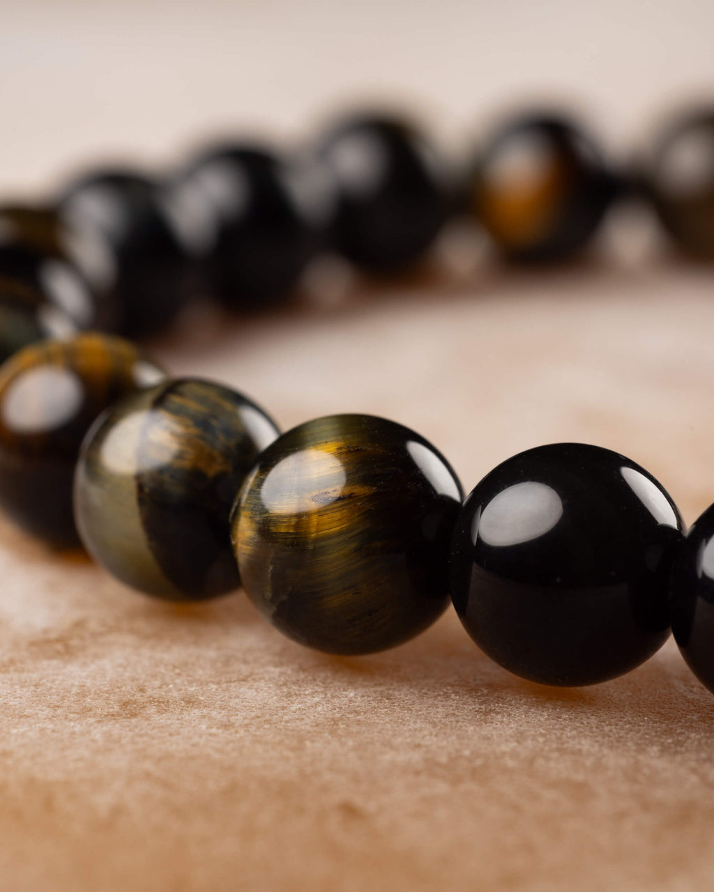 Pulsera de Ojo de Tigre Bicolor en perspectiva, cuentas negras y doradas en fila