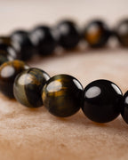 Pulsera de Ojo de Tigre Bicolor en perspectiva, cuentas negras y doradas en fila