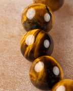 Detalle macro vertical de cuentas de Ojo de Tigre con vetas doradas y oscuras