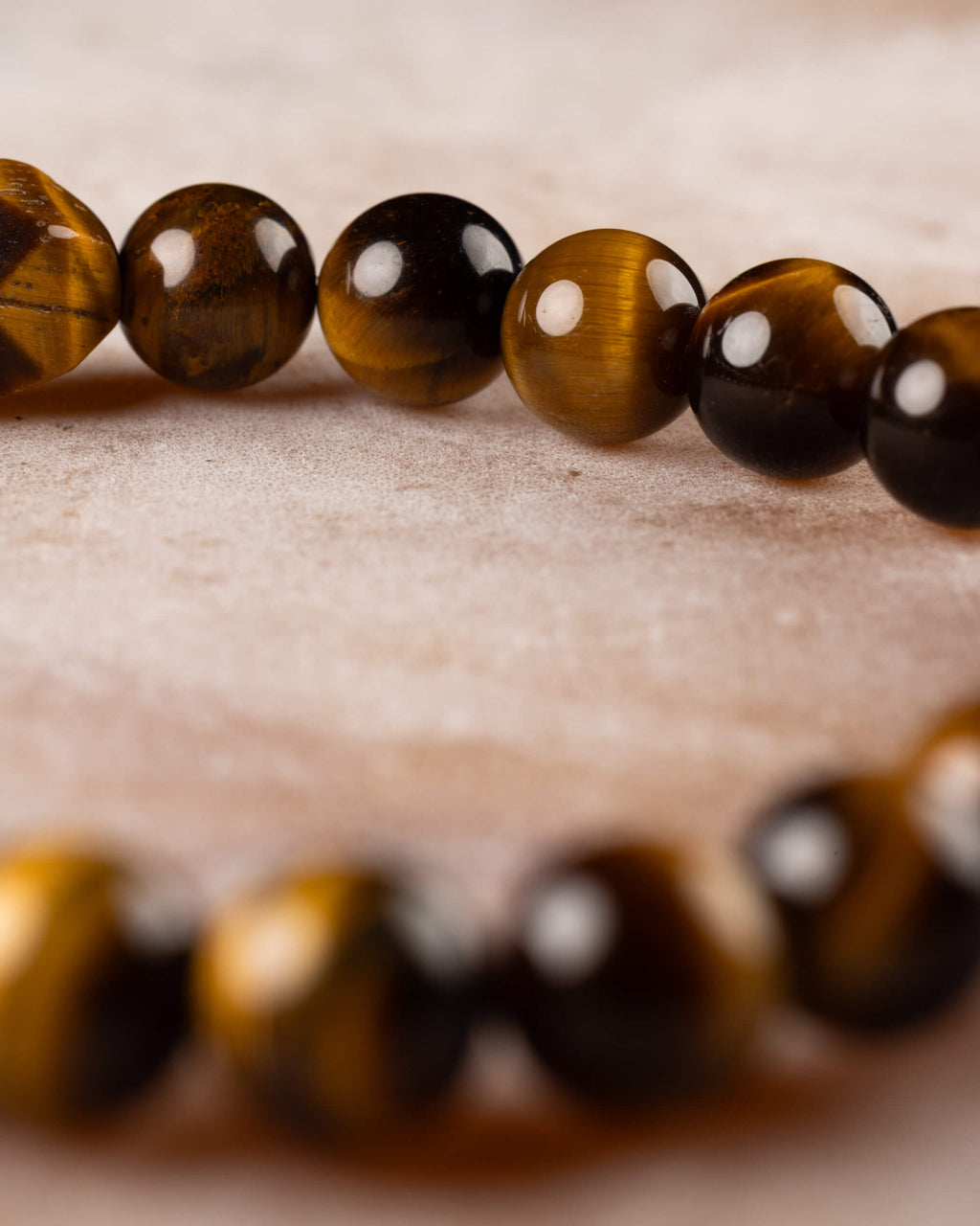 Pulsera de Ojo de Tigre en perspectiva, cuentas doradas en curva sobre superficie clara