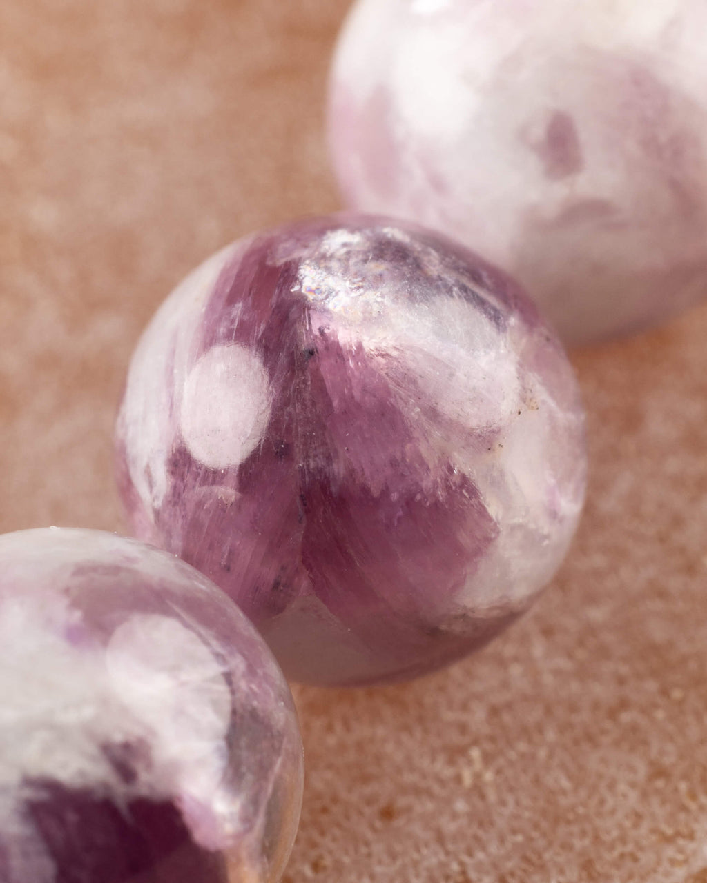 Detalle macro de una cuenta de Turmalina Ciruela con vetas moradas y blancas
