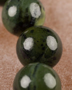 Detalle macro de las cuentas de Jade Verde Oscuro con vetas y manchas claras
