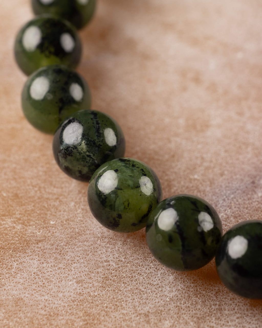 Cuentas de Jade Verde Oscuro en curva, angulo diagonal sobre la mesa