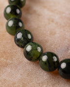 Cuentas de Jade Verde Oscuro en curva, angulo diagonal sobre la mesa