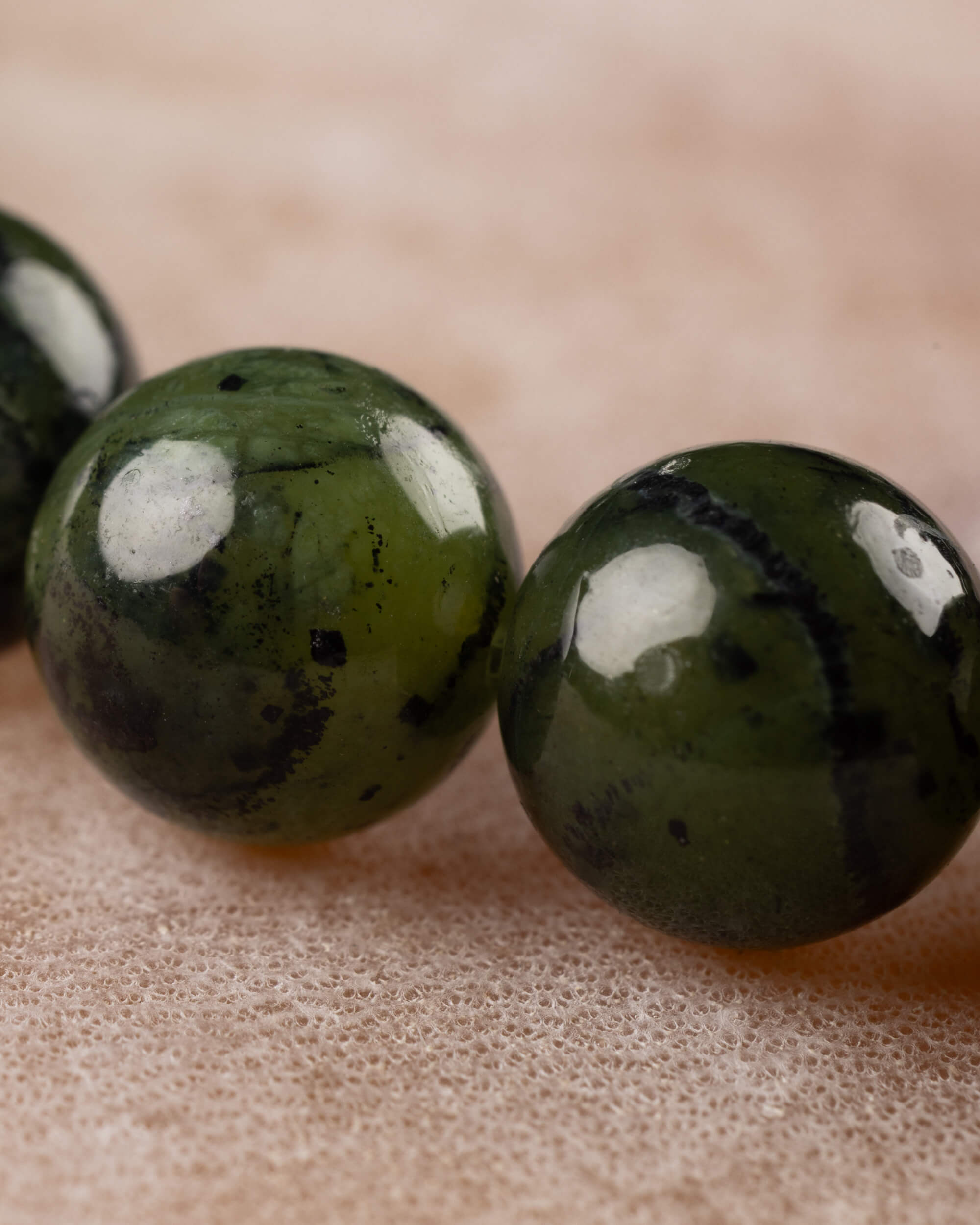 Detalle macro en primer plano de dos cuentas de Jade Verde Oscuro