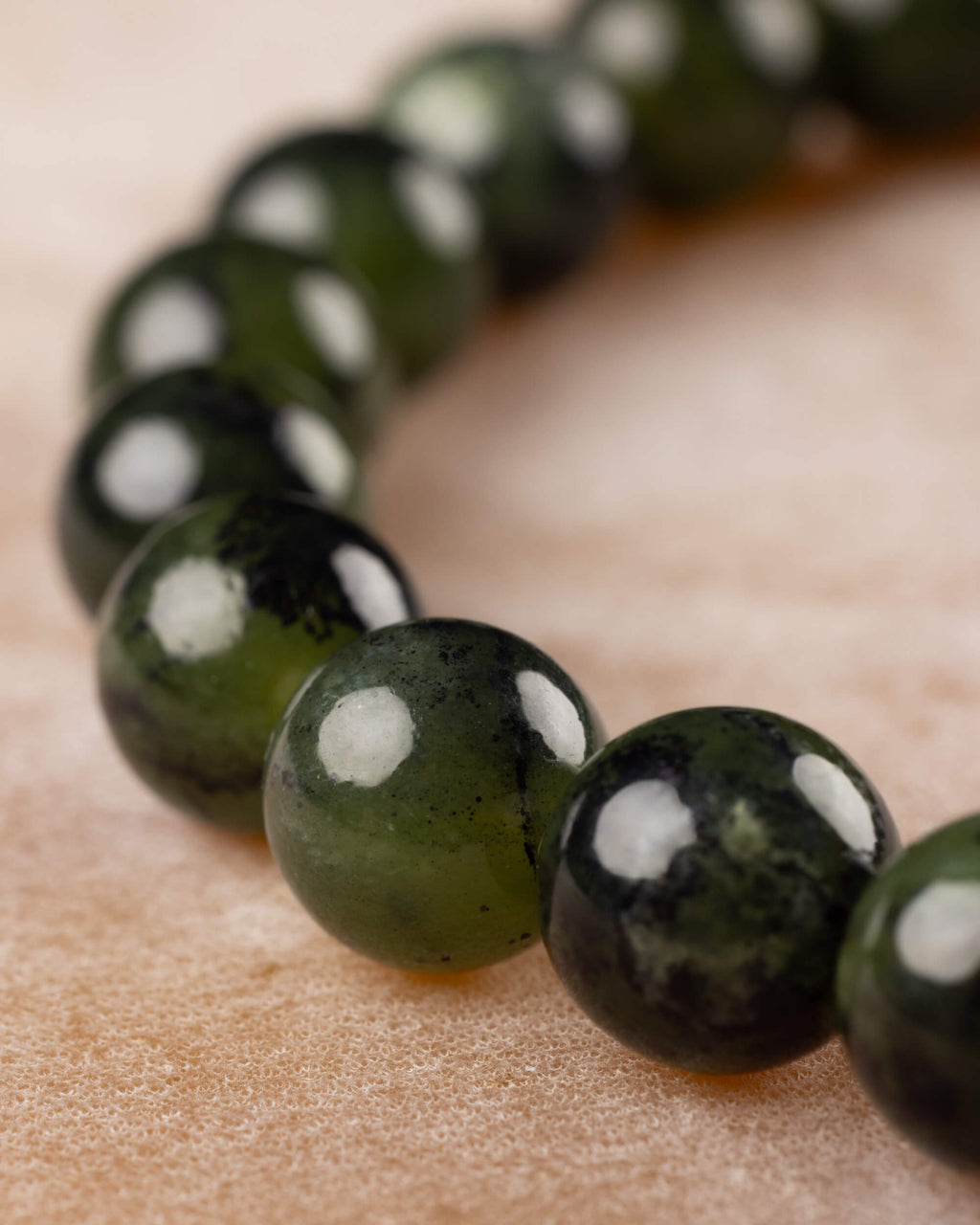 Cuentas de Jade Verde Oscuro en curva, enfoque en el tramo delantero de la pulsera