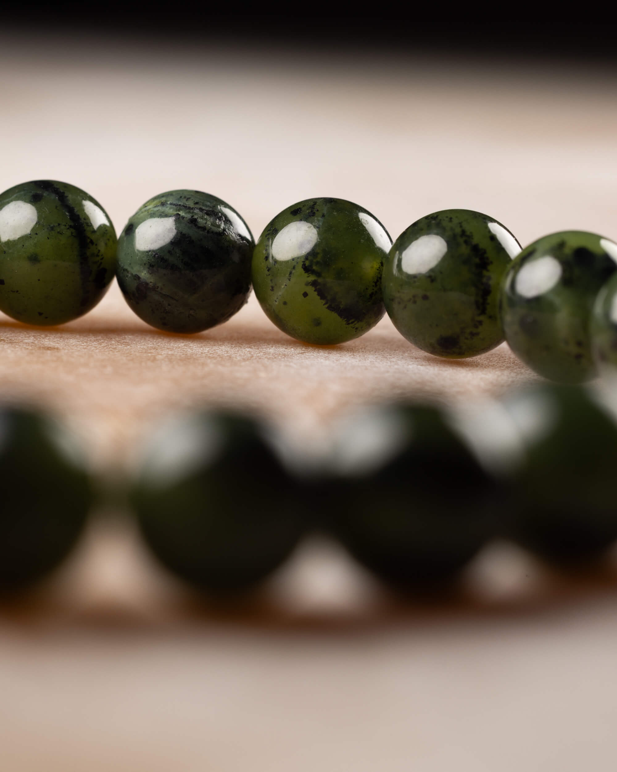 Cuentas de Jade Verde Oscuro en fila con el círculo de la pulsera desenfocado al fondo