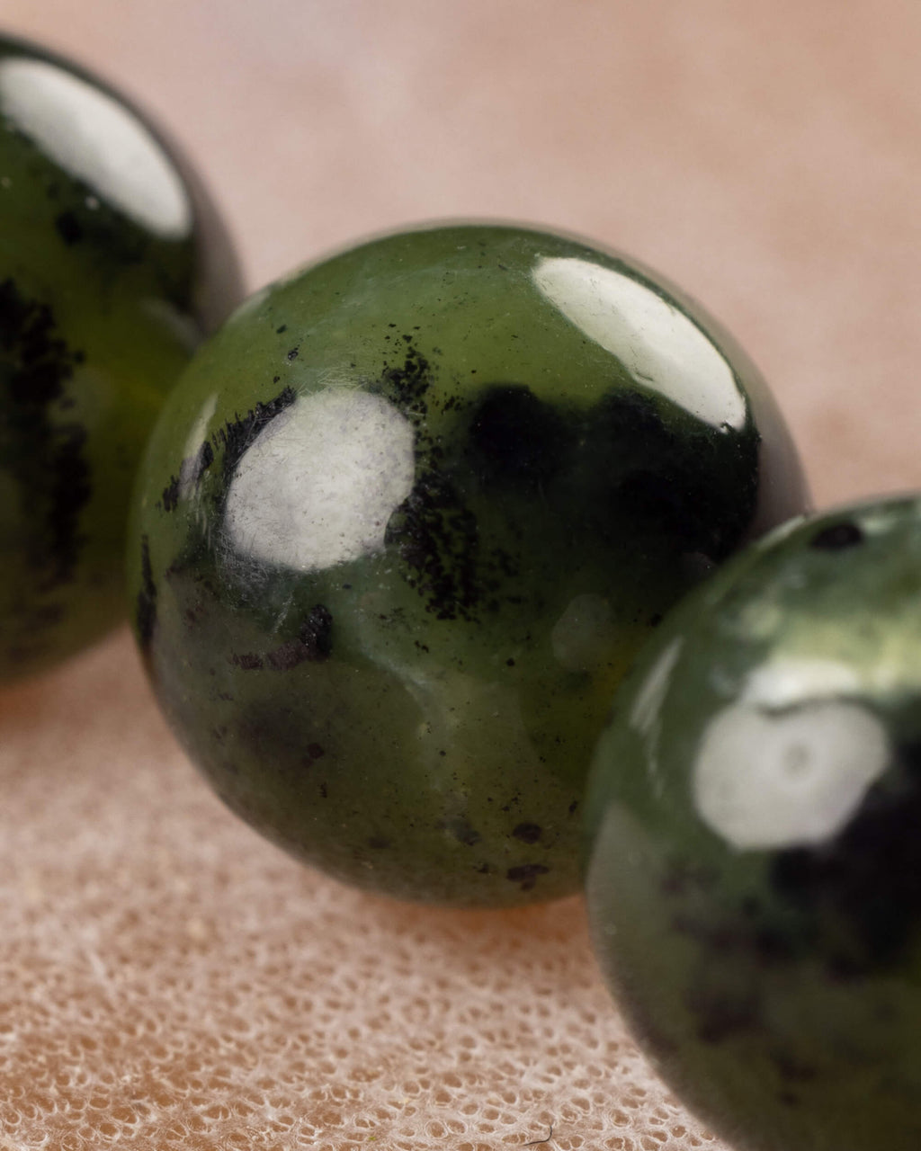 Detalle macro en primer plano de una cuenta de Jade Verde Oscuro con vetas negras
