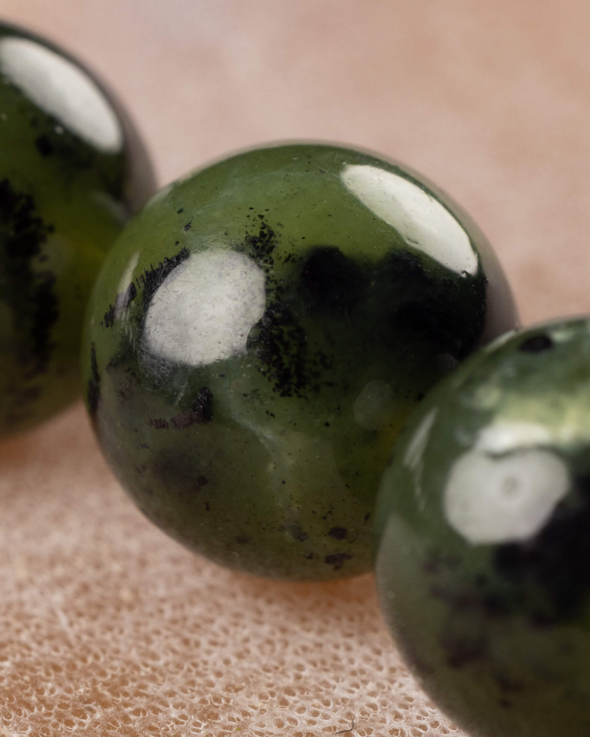 Detalle macro en primer plano de una cuenta de Jade Verde Oscuro con vetas negras
