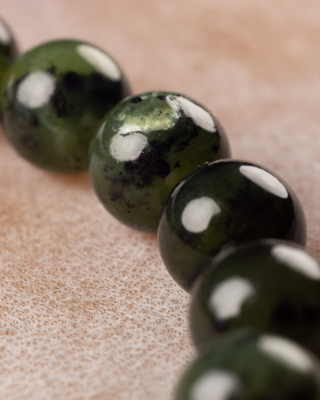 Detalle macro de las cuentas de Jade Verde Oscuro con manchas claras y vetas negras