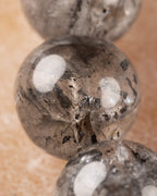 Detalle macro de una cuenta de Cuarzo Diamante de Herkimer con inclusiones negras