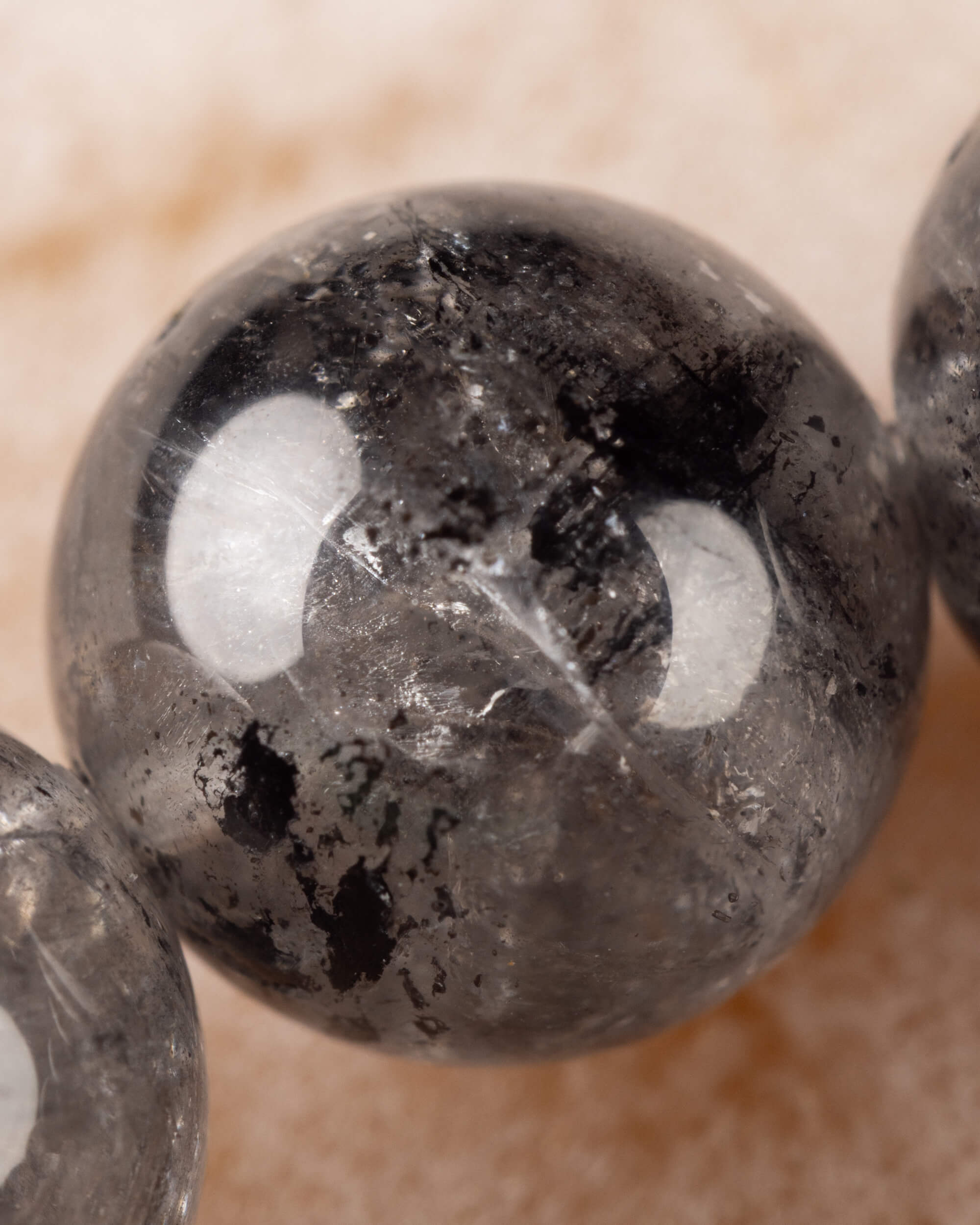 Detalle macro de una cuenta de Cuarzo Diamante de Herkimer con inclusiones oscuras
