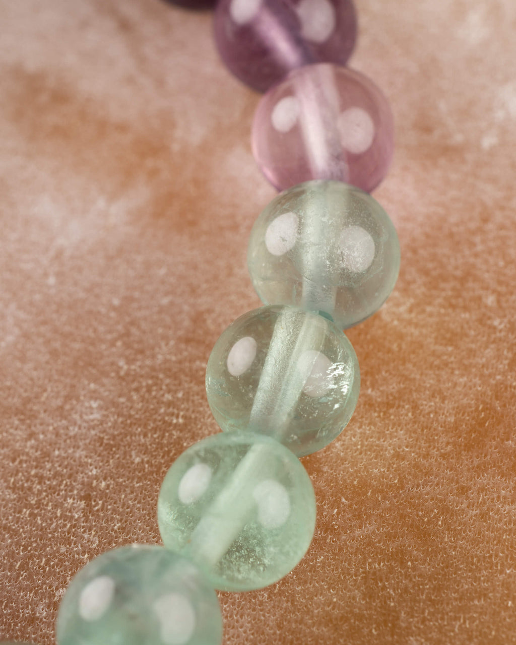 Detalle macro de cuentas de Fluorita en tonos morado y verde con vetas internas