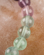 Detalle macro de cuentas de Fluorita en tonos morado y verde con vetas internas