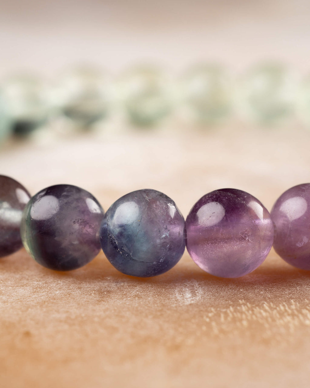 Detalle macro de cuentas de Fluorita en tonos morado, azul y verde en fila