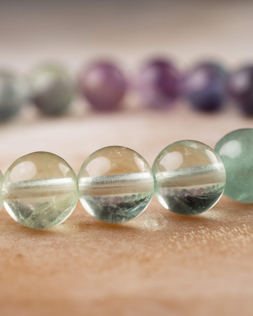 Cuentas verdes translúcidas de Fluorita vistas de cerca con fondo morado difuminado