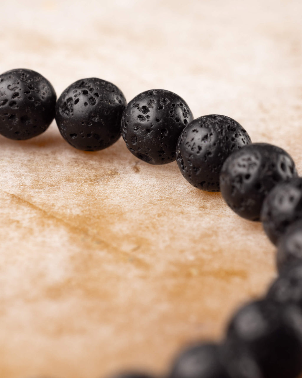 Pulsera de Piedra Volcanica en perspectiva cercana, cuentas porosas en fila