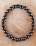 Pulsera de Hematita de 8 mm, pieza completa circular sobre superficie de piedra