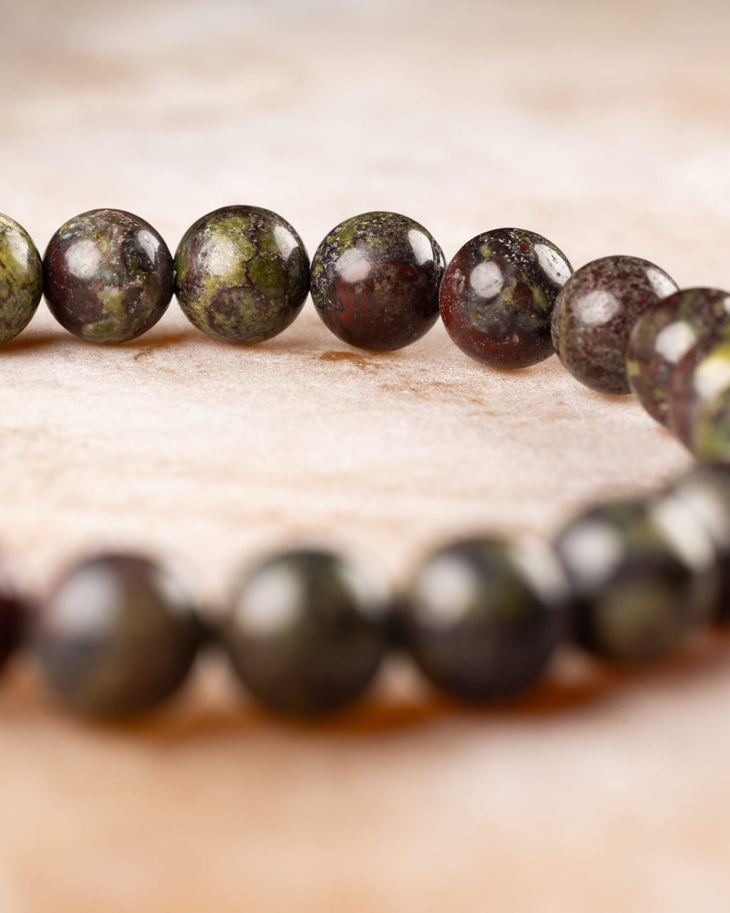 Pulsera de Jaspe Sangre de Dragón vista de perfil sobre mármol claro