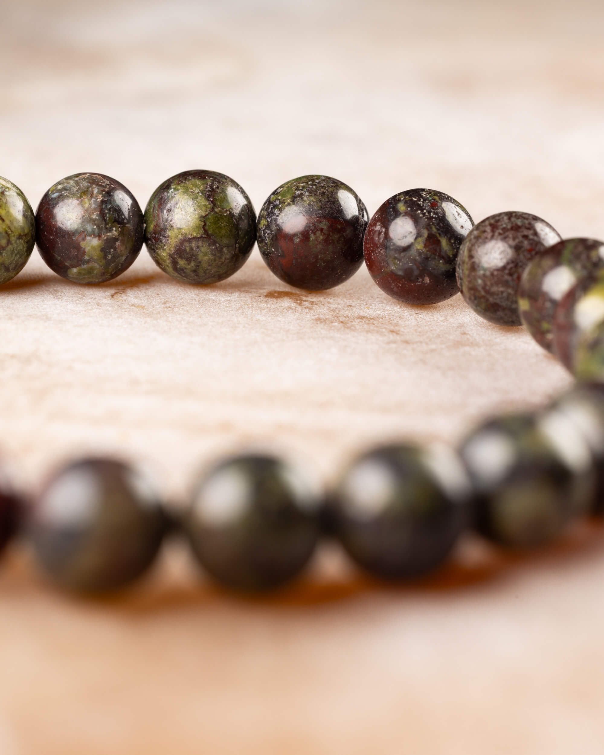Pulsera de Jaspe Sangre de Dragón vista de perfil sobre mármol claro