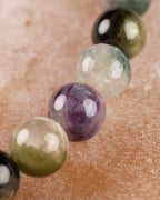 Detalle macro de cuentas moradas y verde oliva junto a una cuenta negra brillante