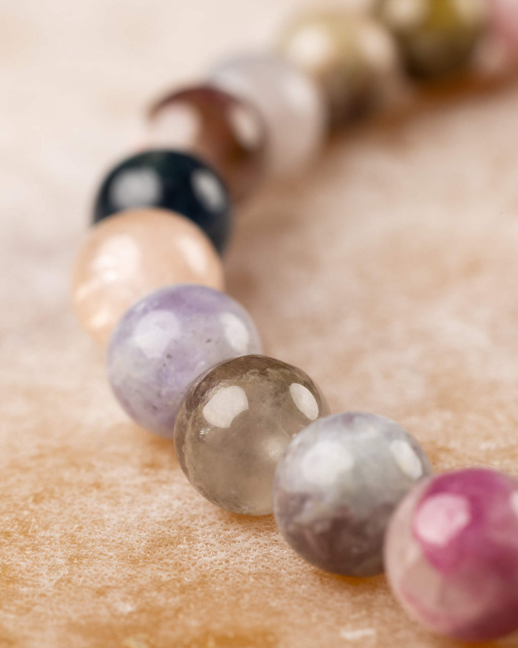 Pulsera de Turmalina Multicolor, curva de cuentas en perspectiva sobre madera clara