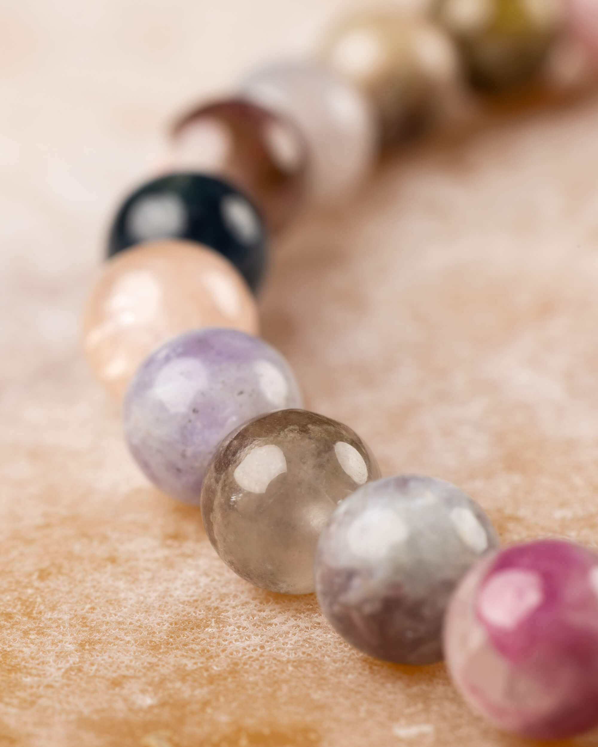 Pulsera de Turmalina Multicolor, curva de cuentas en perspectiva sobre madera clara
