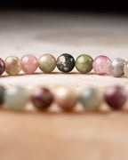 Pulsera de Turmalina Multicolor abierta sobre fondo oscuro con textura clara