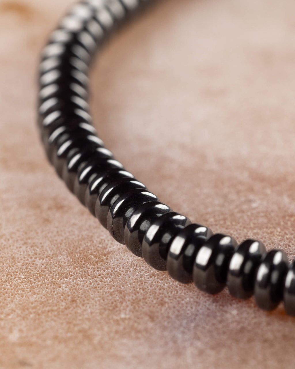 Pulsera de Hematita en discos en perspectiva curva sobre superficie de piedra