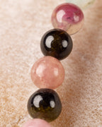 Detalle macro de cuentas de Turmalina rosa, negra y rosa pálido en fila vertical