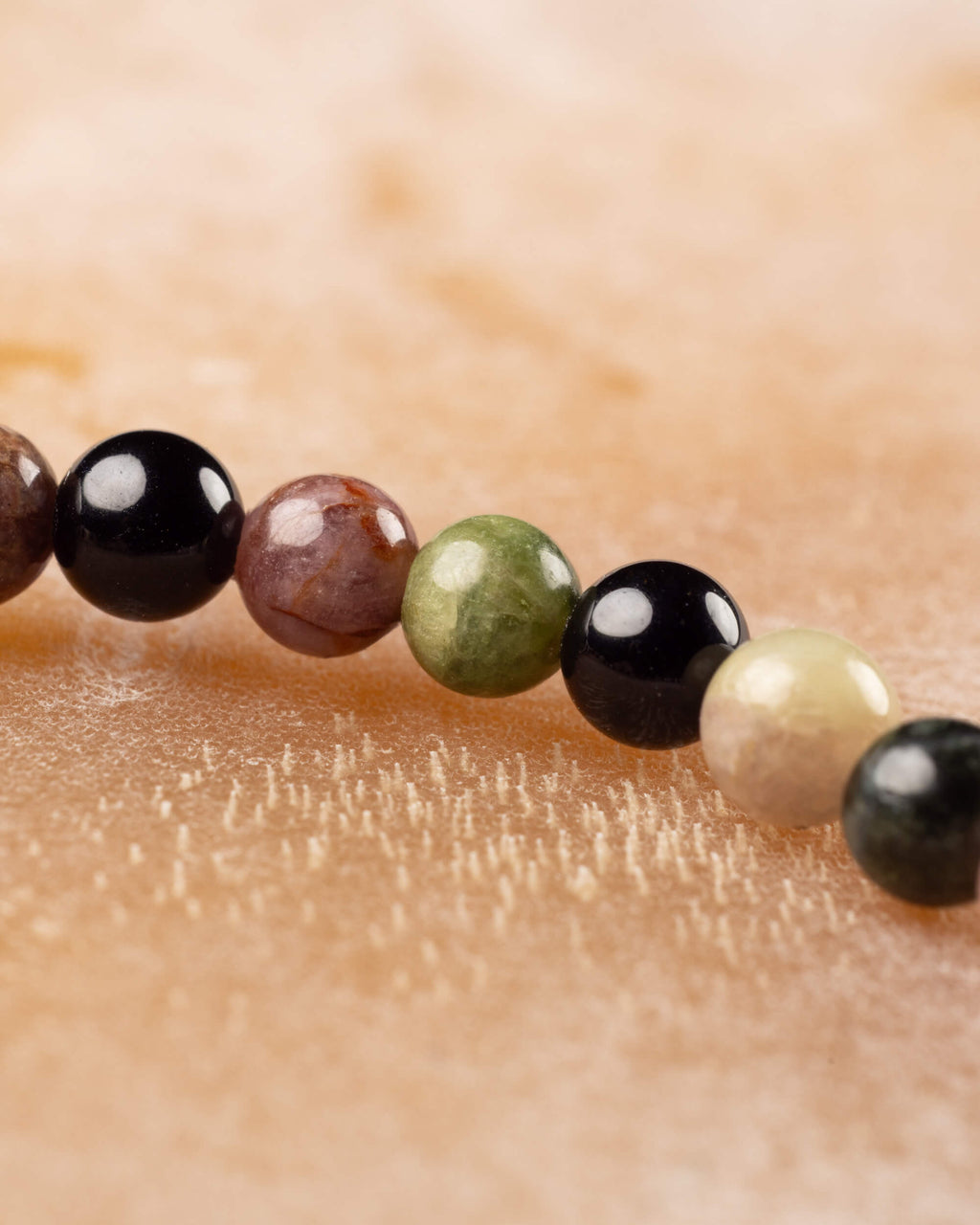 Detalle macro de cuentas de Turmalina café, negra, verde y crema en fila