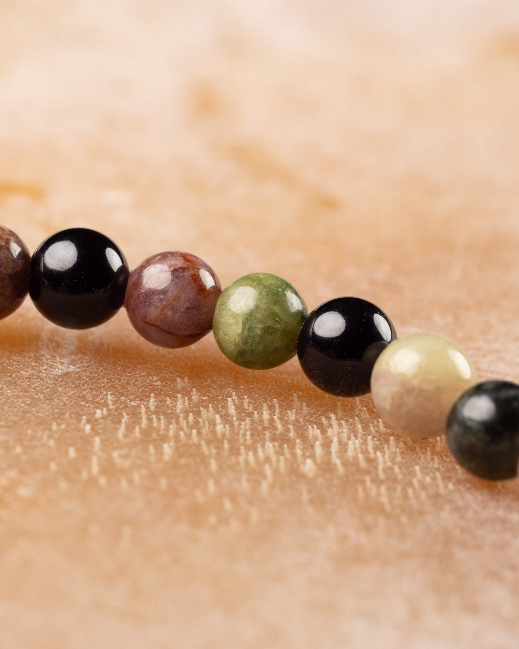 Detalle macro de cuentas de Turmalina café, negra, verde y crema en fila