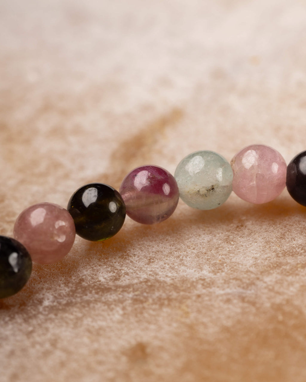 Detalle macro de cuentas de Turmalina rosa, negra, morada y azul claro en fila