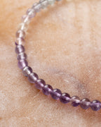 Pulsera de Fluorita Arcoíris mostrando el degradado morado sobre superficie clara