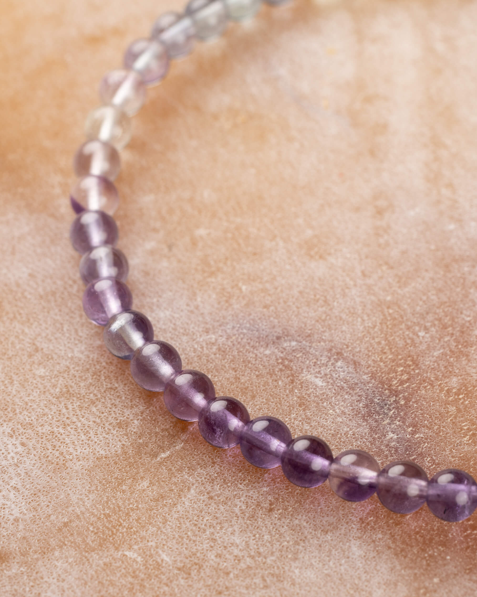 Pulsera de Fluorita Arcoíris mostrando el degradado morado sobre superficie clara