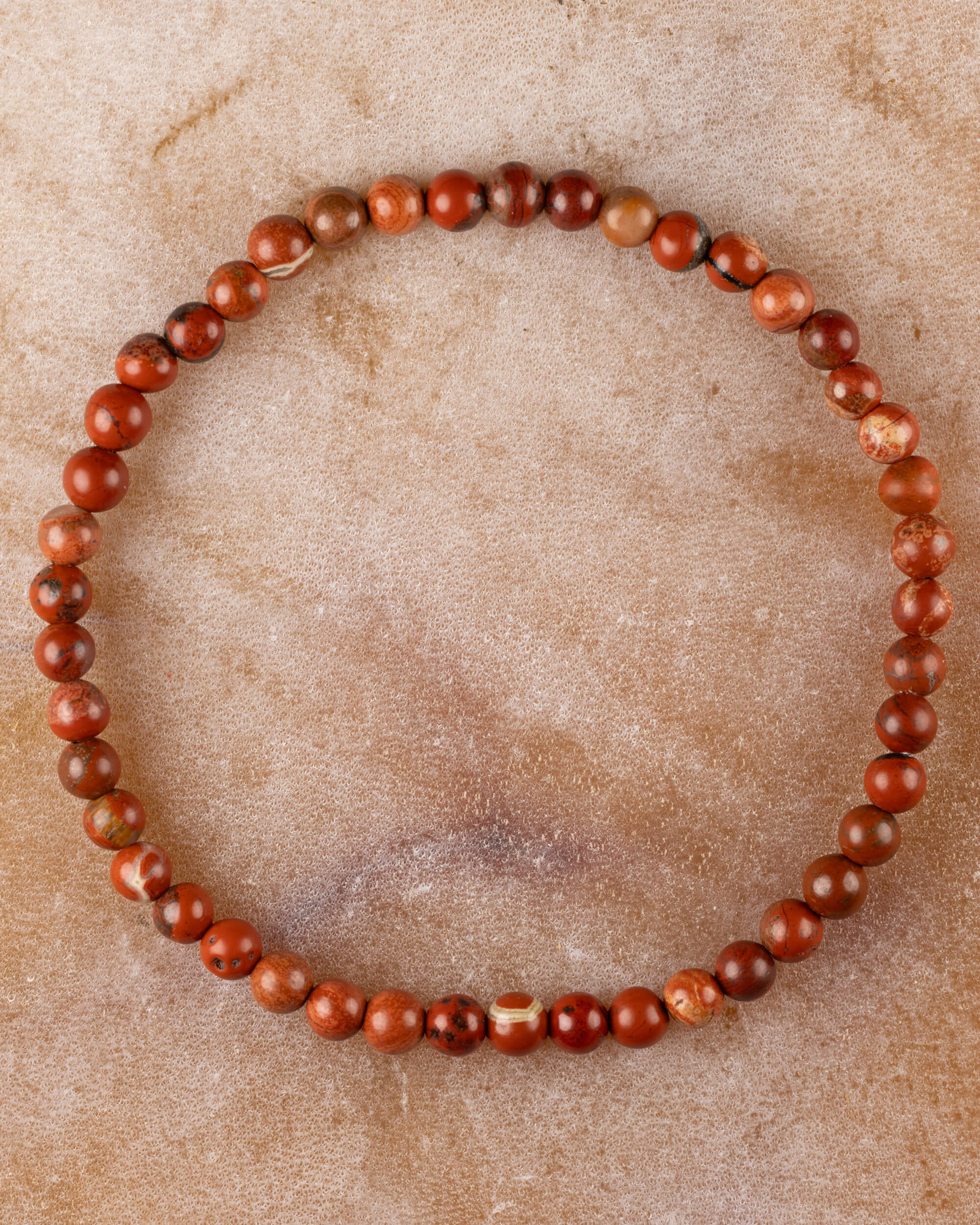Pulsera de Jaspe Rojo de 4 mm, pieza completa en círculo sobre superficie de piedra clara