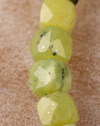 Detalle macro vertical de las cuentas facetadas de Jade Verde con motas oscuras