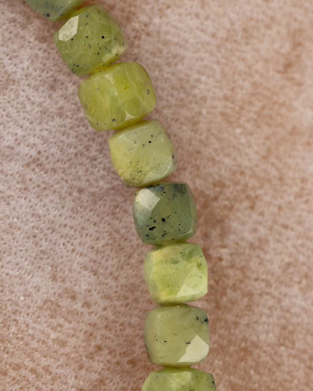 Detalle macro de las cuentas facetadas de Jade Verde en tonos verde y amarillo