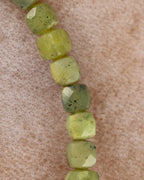 Detalle macro de las cuentas facetadas de Jade Verde en tonos verde y amarillo