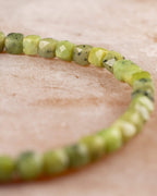 Detalle macro vertical de las cuentas facetadas de Jade Verde con motas oscuras