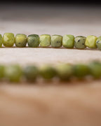 Cuentas de Jade Verde facetadas en fila con el círculo de la pulsera desenfocado al fondo