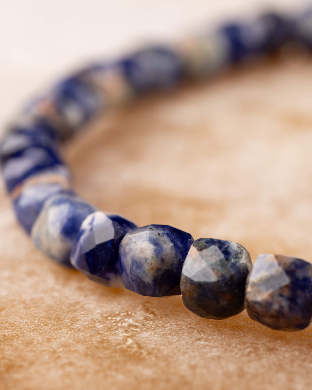 Pulsera de Sodalita en perspectiva, curva de cuentas facetadas sobre madera