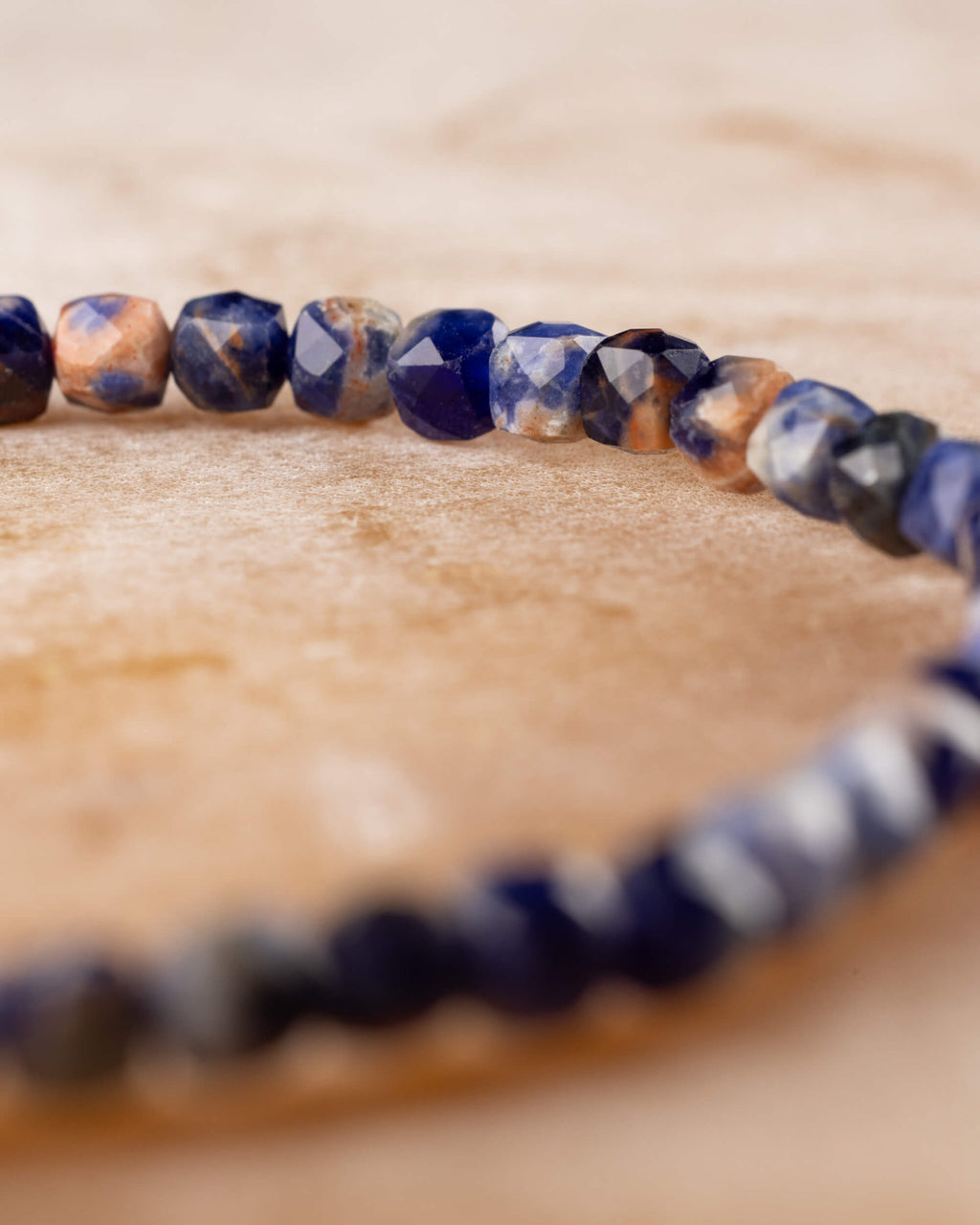 Pulsera de Sodalita en perspectiva, cuentas facetadas al frente sobre madera clara