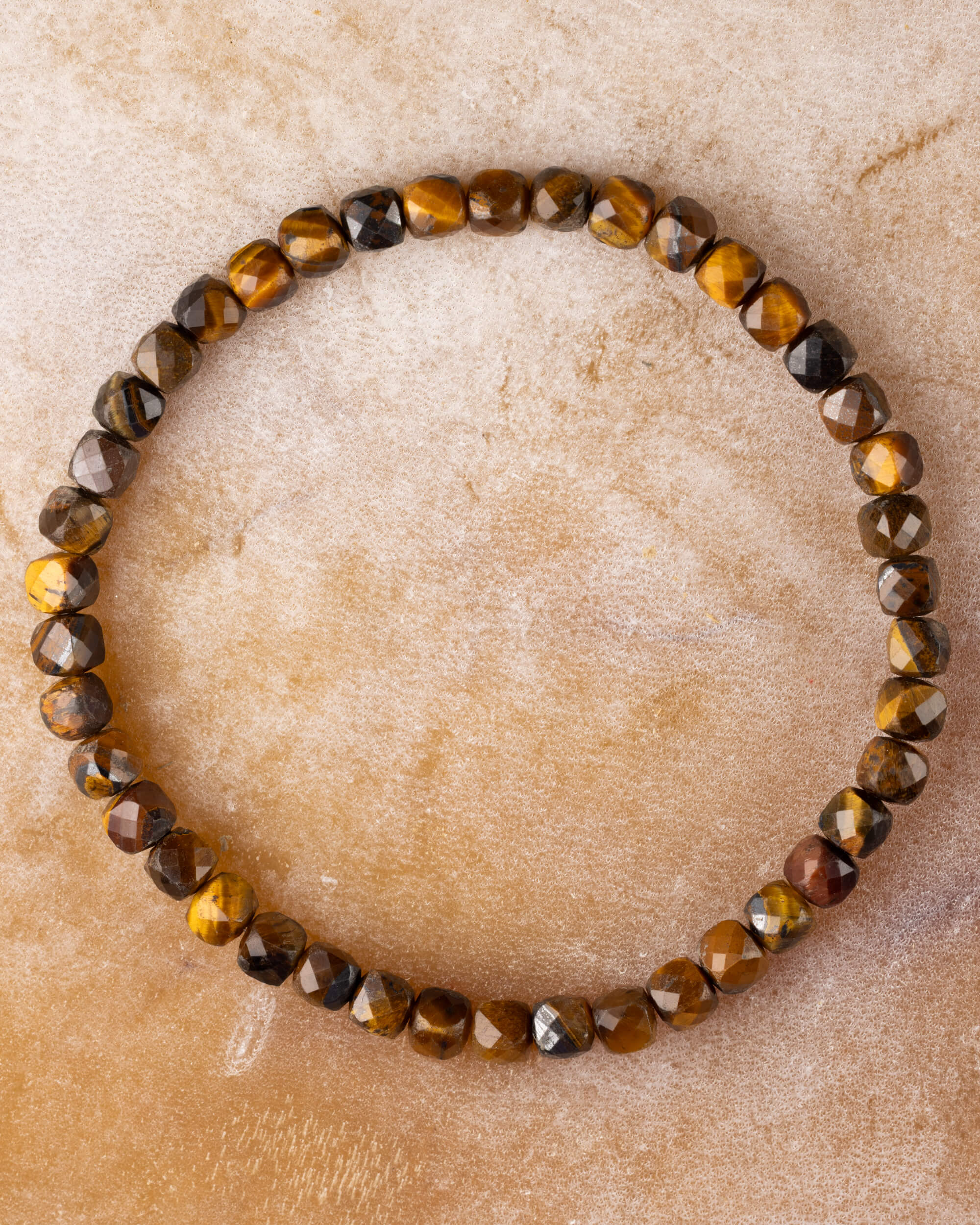 Pulsera de Ojo de Tigre facetada, pieza completa en círculo sobre superficie clara