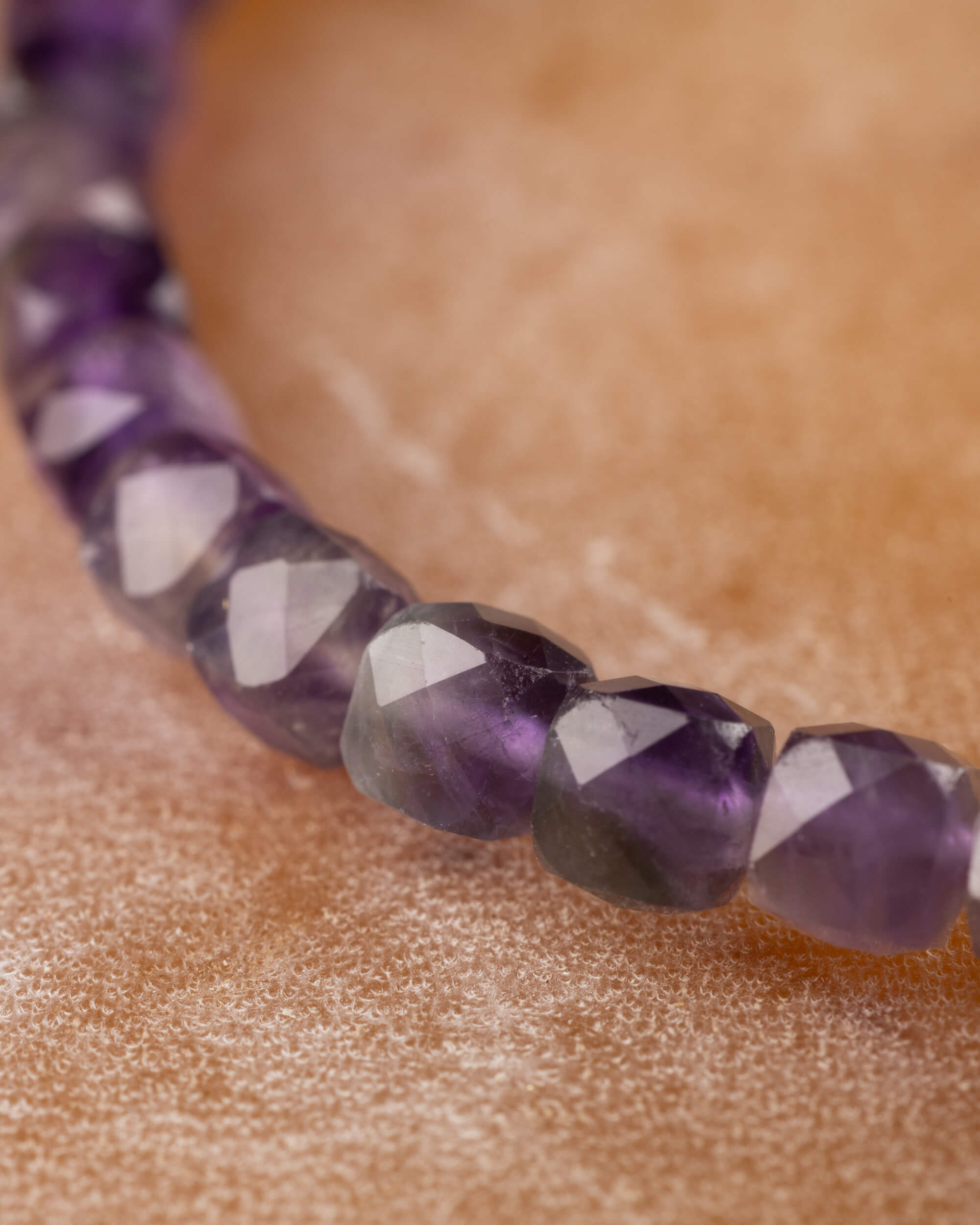Detalle macro de las cuentas de Amatista en violeta oscuro sobre mármol