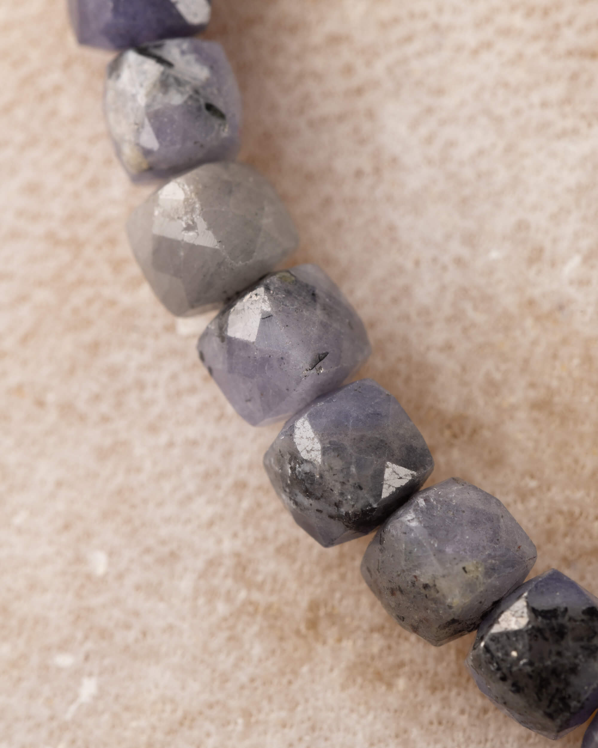Pulsera de Tanzanita en perspectiva, cuentas facetadas gris y violeta al frente