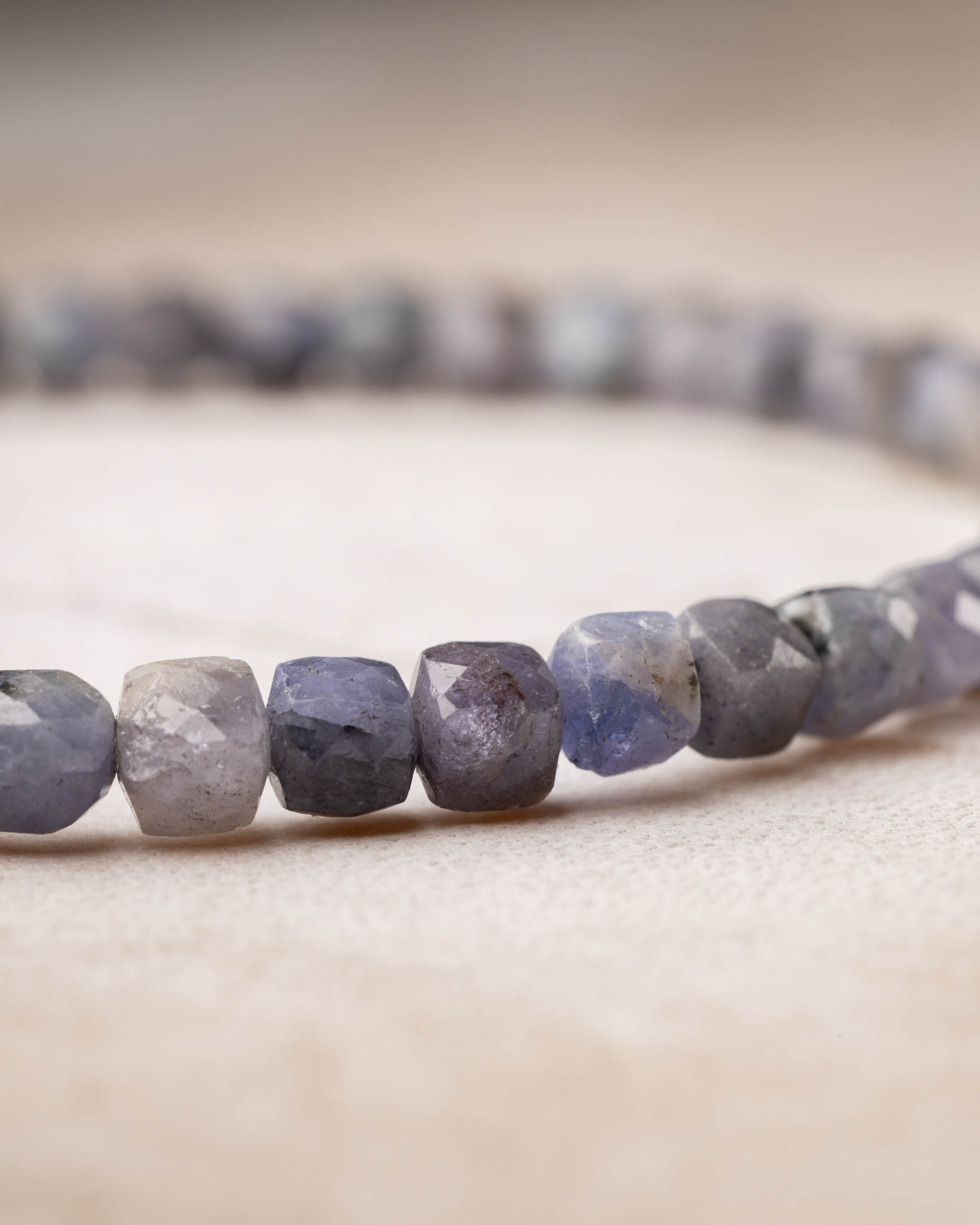 Pulsera de Tanzanita en perspectiva, cuentas facetadas gris y violeta al frente