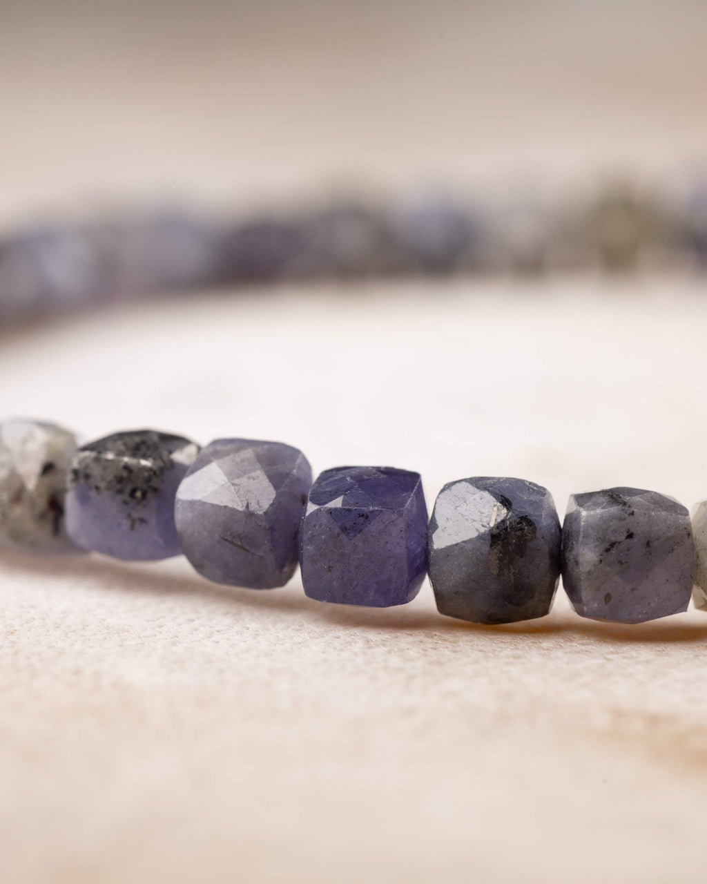 Pulsera de Tanzanita facetada extendida sobre fondo claro con textura suave