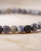 Detalle macro de cuentas facetadas de Tanzanita con tonos gris y violeta